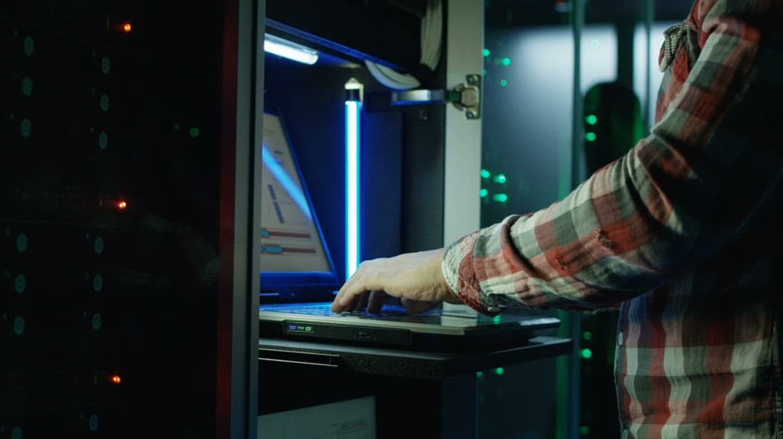Cloud engineer configuring infrastructure on a laptop in a data centre