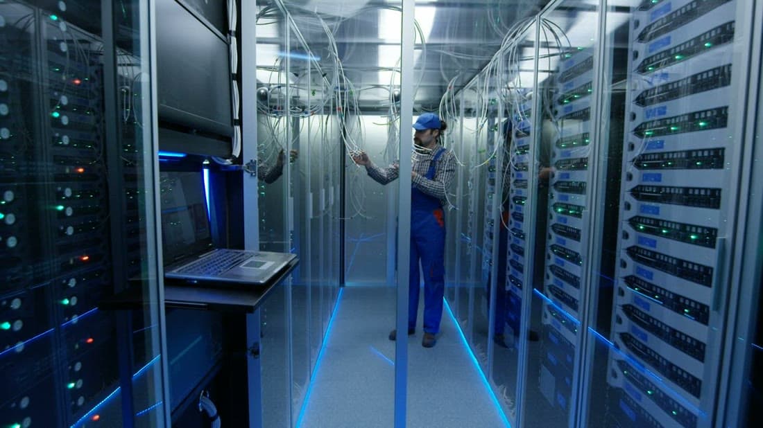 IT technician managing network cables and server racks in a data centre